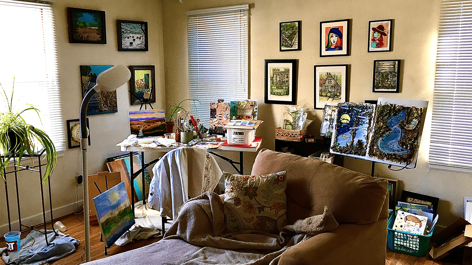 Art studio filled with colorful paintings, an easel, and art supplies. A cozy couch with a patterned pillow invites creativity and relaxation.