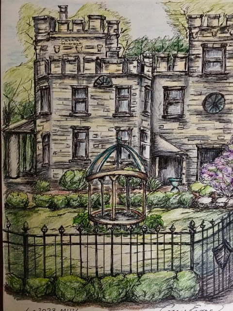 Victorian-style mansion surrounded by greenery, featuring a central gazebo and a wrought-iron fence, highlighting its ornate architecture and landscaping.